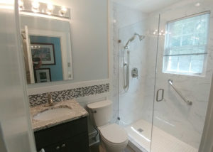 A remodeled bathroom with granite countertop, glass and tile shower